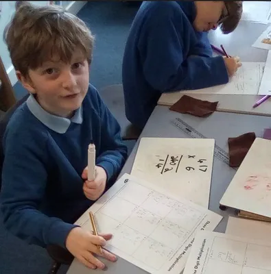 A group of kids sitting at a table with paper and pens

Description automatically generated
